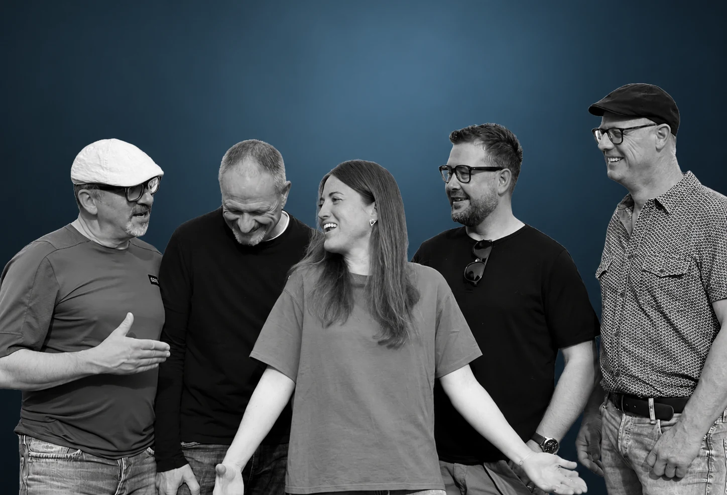 Die fünf Bandmitglieder lachend vor blauem Hintergrund, Schwarz-Weiss-Aufnahme